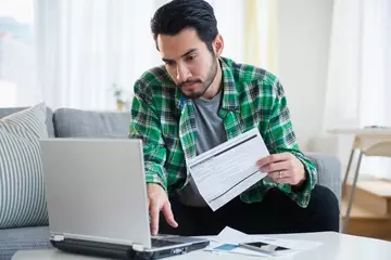 Man at computer with bills money stress
